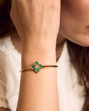 Gold bracelet with green flower charm on wrist